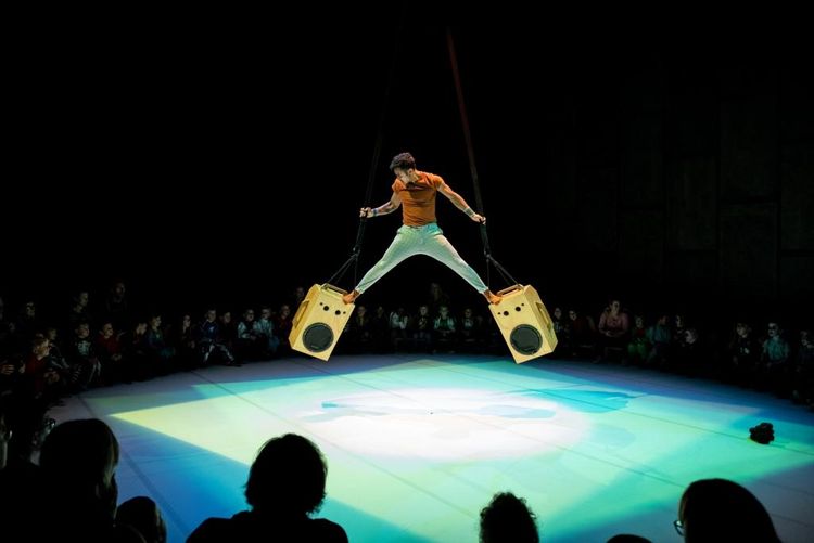 Un artiste de la compagnie flamande Grensgeval en équilibre sur des haut-parleurs suspendus dans les airs